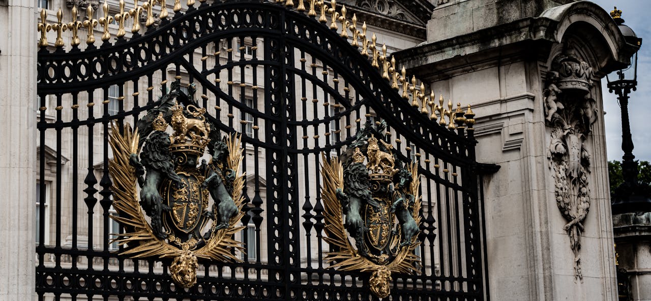A detailed view of the ornate iron gate with royal crests at Buckingham Palace, London.